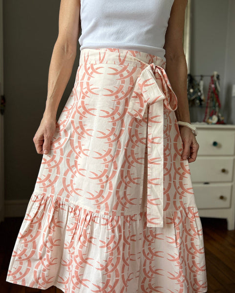 A person wearing a peach-colored wrap skirt with a rhino and horn pattern, paired with a white top.