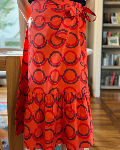 A person wearing a red and purple geometric patterned skirt with a wrap-around style.