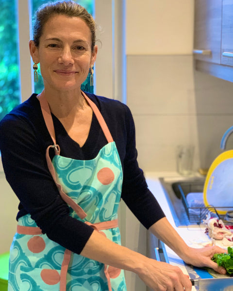 Woman wearing a turquoise and terracotta hand block-printed apron in a kitchen