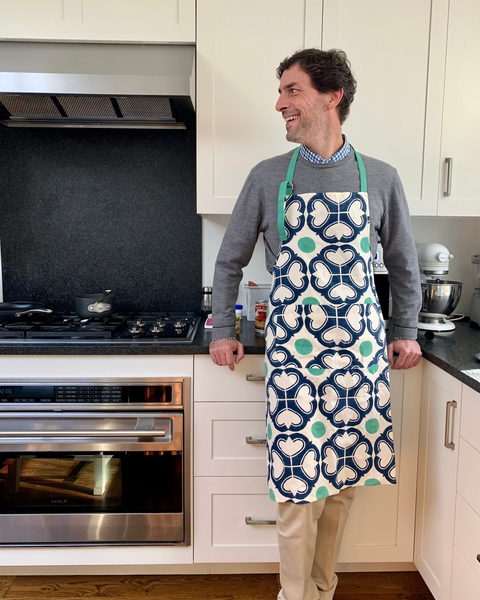 Man wearing a navy blue, green, and off-white block-printed apron in a kitchen