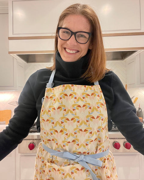 Woman wearing a hand block-printed apron with adjustable ties and pockets in a kitchen setting