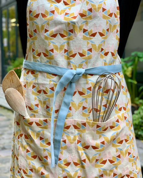 Person wearing a hand block-printed apron with adjustable ties and pockets that hold kitchen utensils
