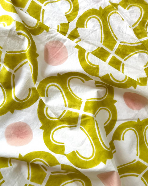 Close-up of a wrap skirt with a geometric pattern in yellow and pink on an off-white background.