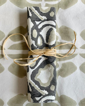 Gray, khaki, and white hand block-printed wild dog napkin rolled up with rafia on sand / khaki and cream table runner