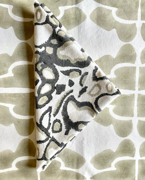 Gray, khaki, and white hand block-printed wild dog napkin folded on sand / khaki and cream table runner