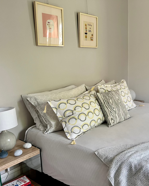Organic cotton linen hand block-printed pillow sham with gray and butter yellow pattern and yellow tassels and gray and white faux bois pillow on luxurious bed in pretty bedroom