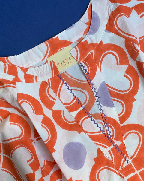 Close-up of hand-embroidered neckline on coral, lavender, and white hand block-printed short kaftan dress 