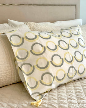 Organic cotton linen hand block-printed pillow sham with gray and butter yellow pattern and yellow tassels on luxurious bed
