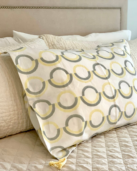 Organic cotton linen hand block-printed pillow sham with gray and butter yellow pattern and yellow tassels on luxurious bed
