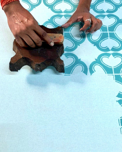 Man hand block-printing turquoise and terracotta condor organic cotton fabric for aprons