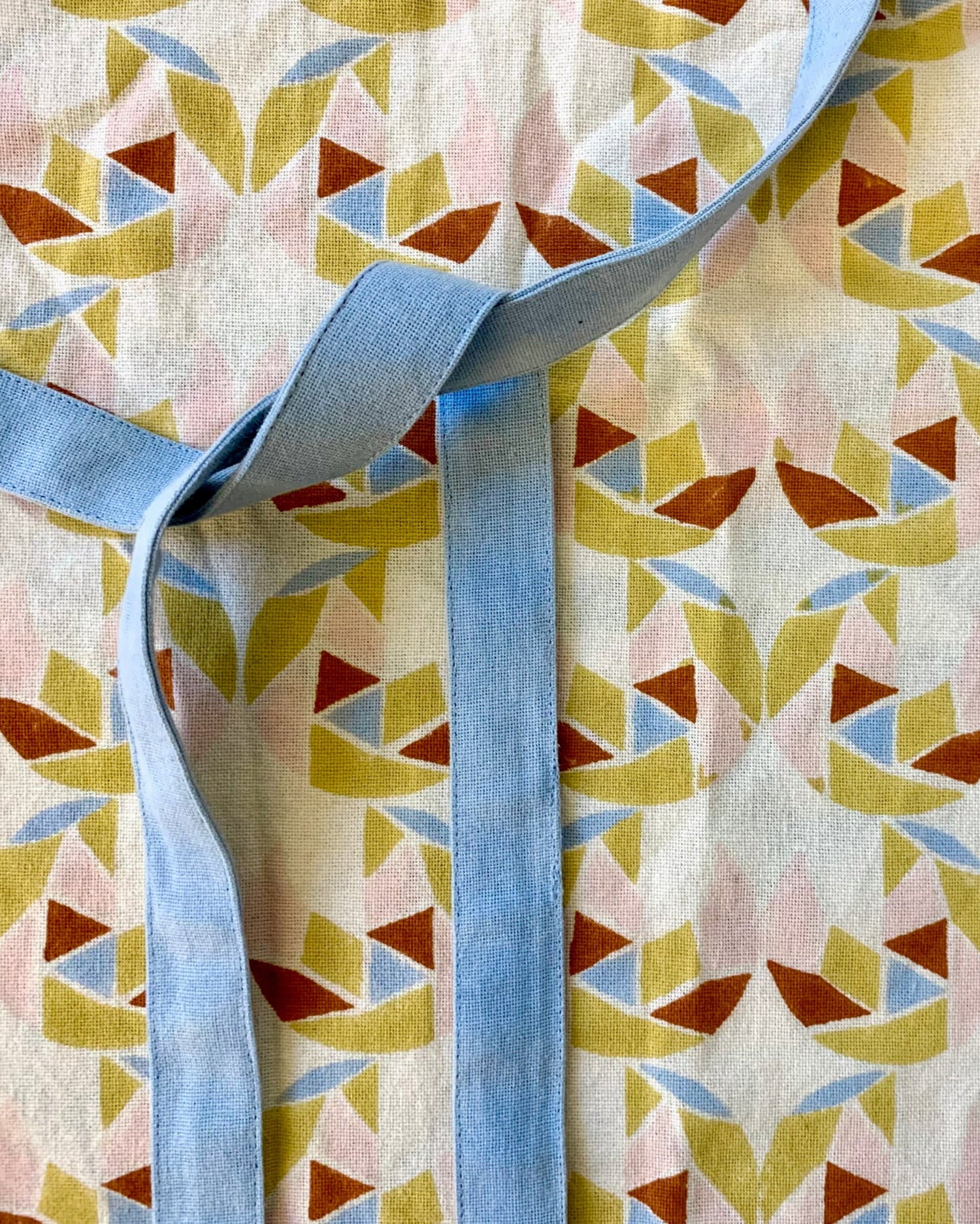 Close-up of a hand block-printed apron with adjustable ties and pockets