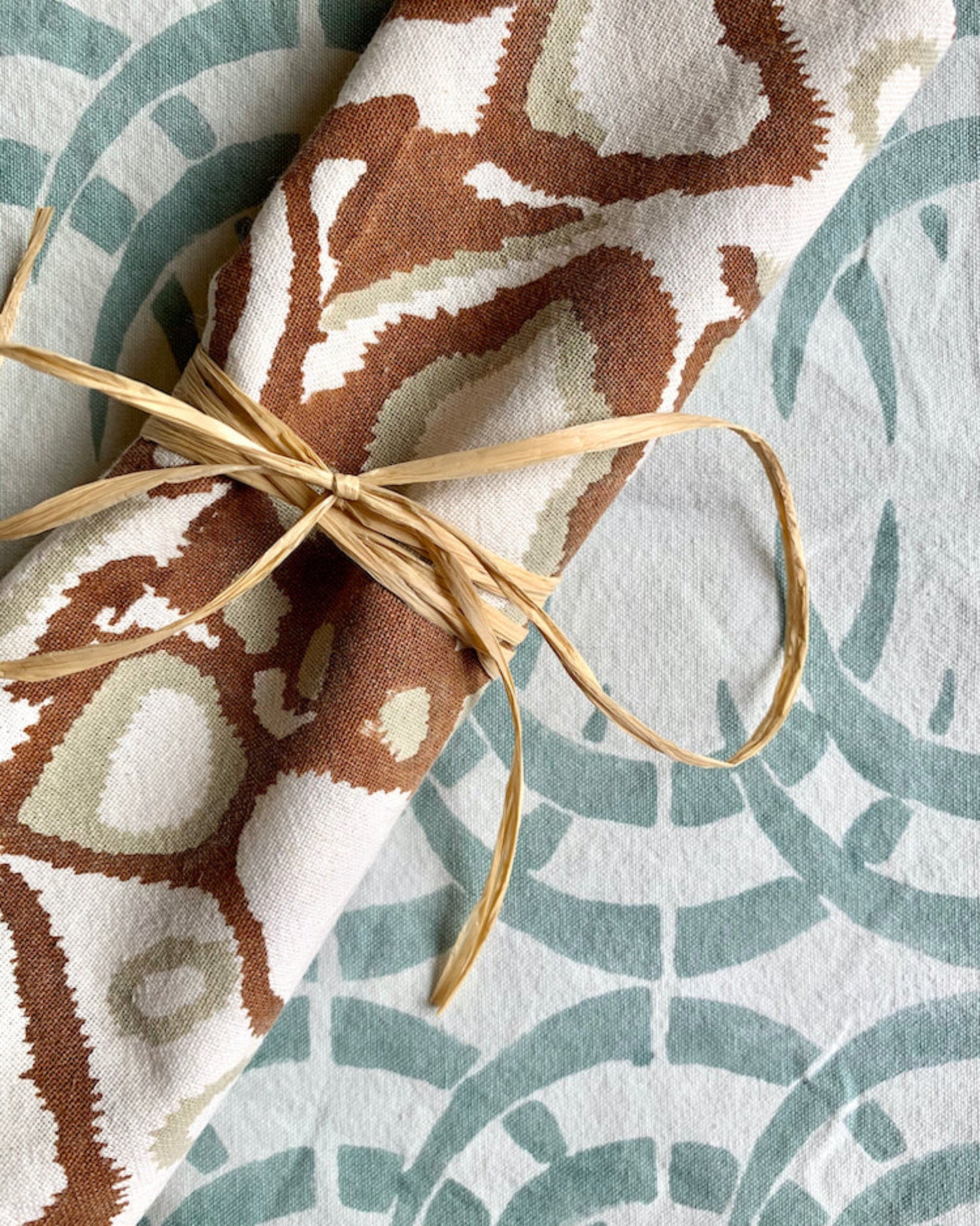 Rust wild dog napkin on sage blue and ice blue rhino print table runner