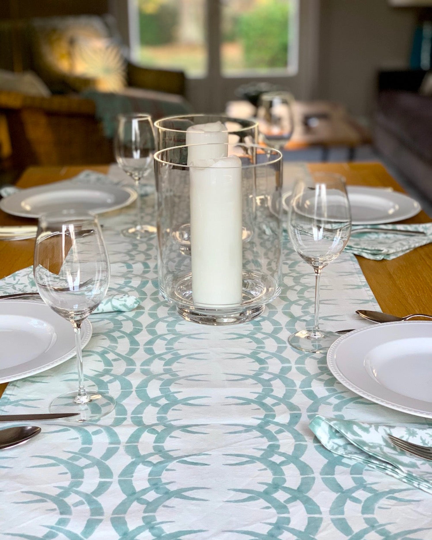 Table set with wine glasses, plates, candles, and sage blue and ice blue rhino print table runner