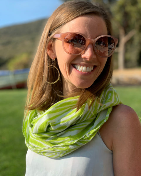 A person smiling and wearing a chartreuse and ice blue faux bois infinity scarf and sunglasses