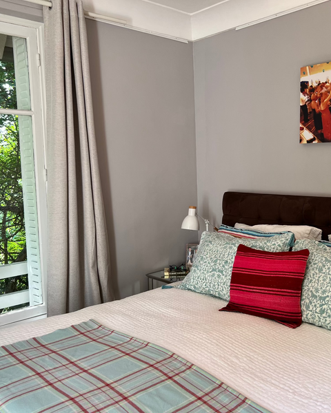 Aqua / sage blue and ice blue hand block-printed organic cotton linen jaguar print pillow sham with tassels on luxurious bed with pink wool pillow throw, and open french window