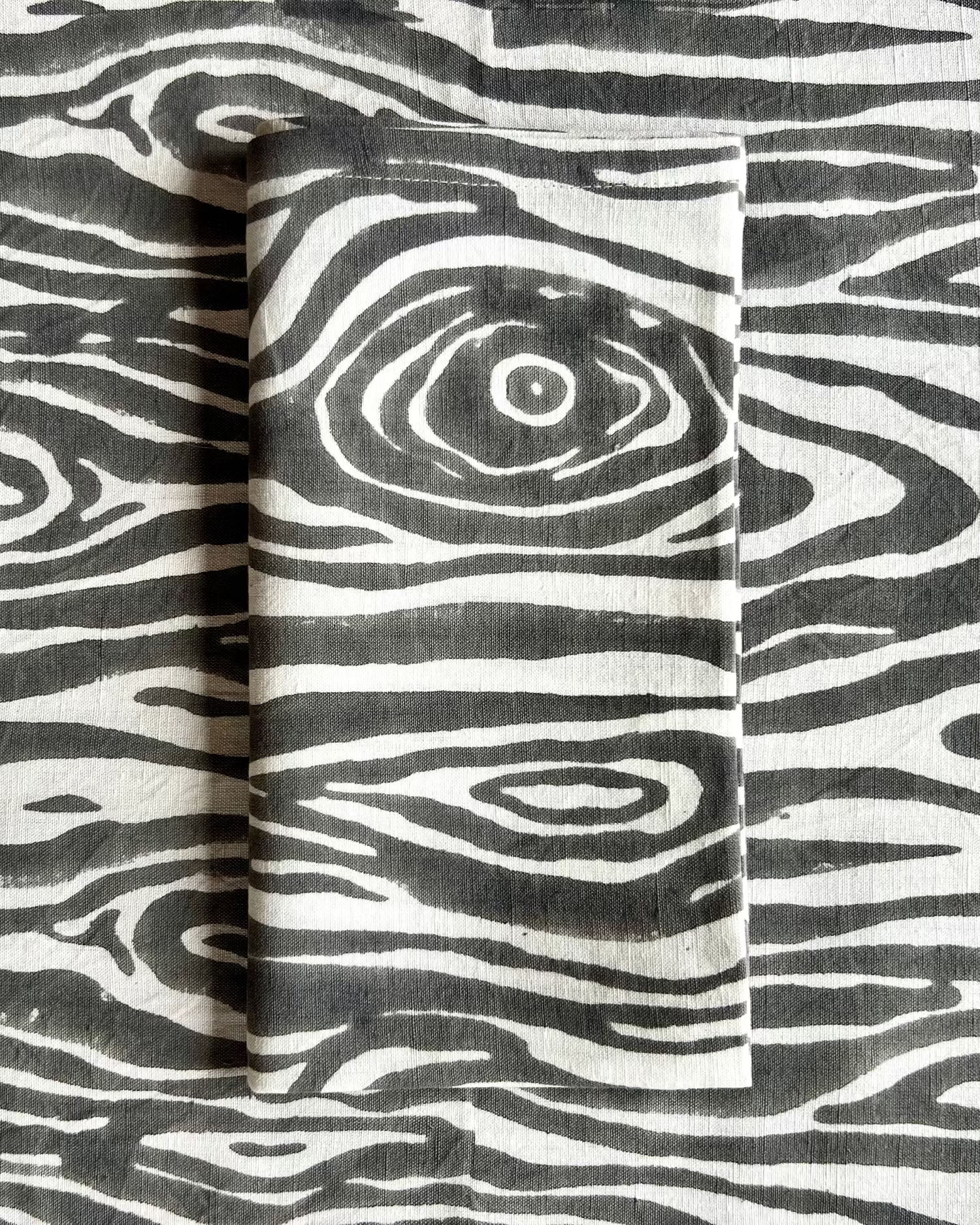 A gray and white faux bois hand block-printed organic cotton linen folded napkin and table runner 