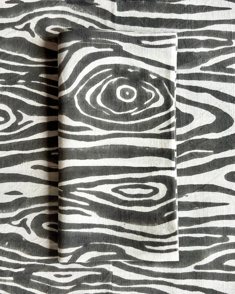 A gray and white faux bois print cotton linen napkin on a faux bois table runner
