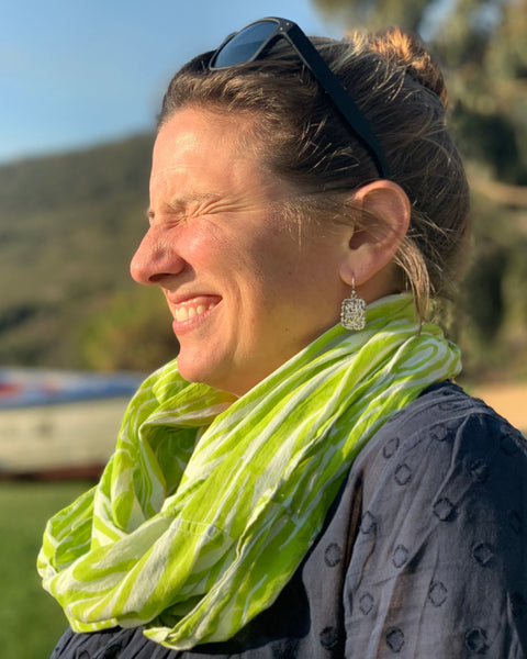 A person smiling and wearing a chartreuse and ice blue faux bois infinity scarf and sunglasses